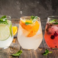 Drei Glaeser Gin mit Minze, Orangen, Limetten und Beeren