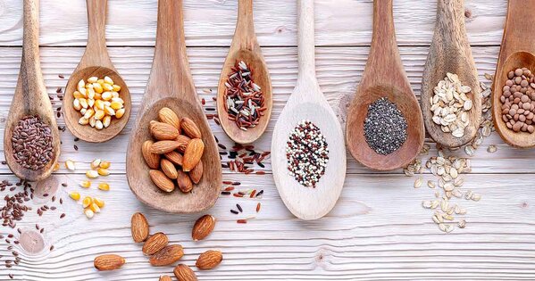 Verschiedene Holzlöffel mit verschiedenen Trockenfruechte befüllt
