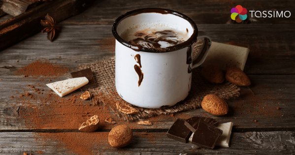 Heißer Kakao in einer Tasse und daneben liegt Schokolade und Kakaobohnen